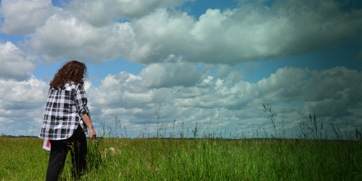 Michelle walking in a field holding her book